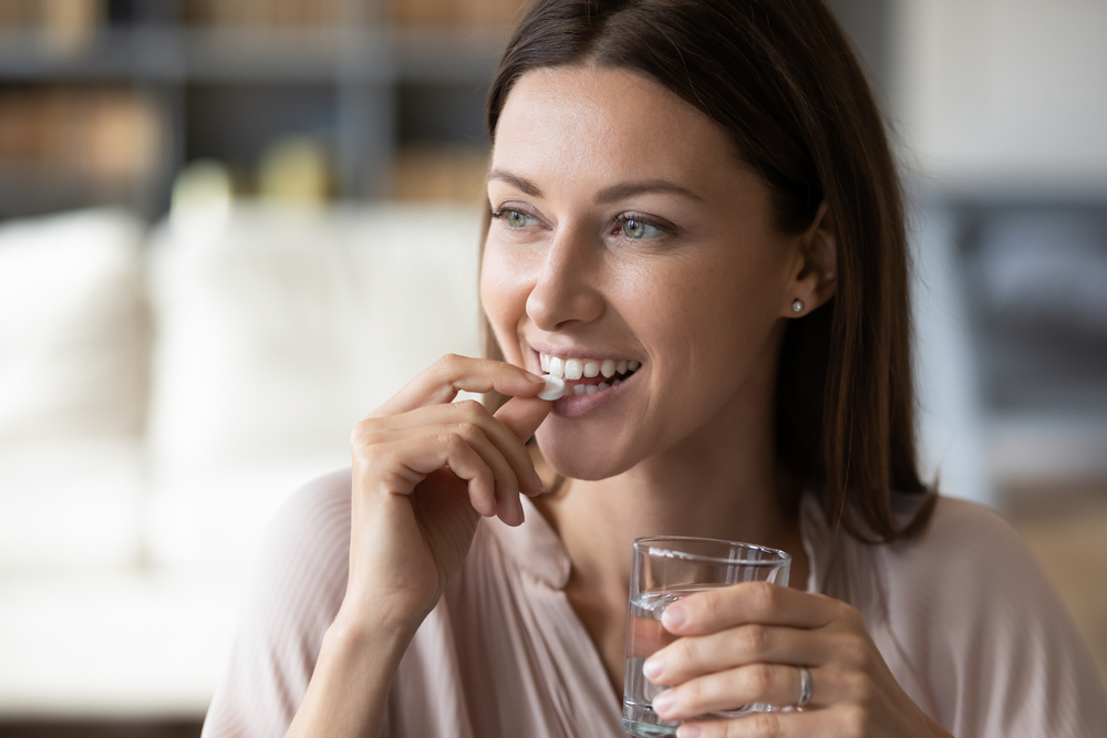 Mulher tomando remédio e sorrindo