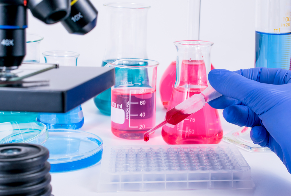 Objetos de laboratório e uma seringa com sangue.